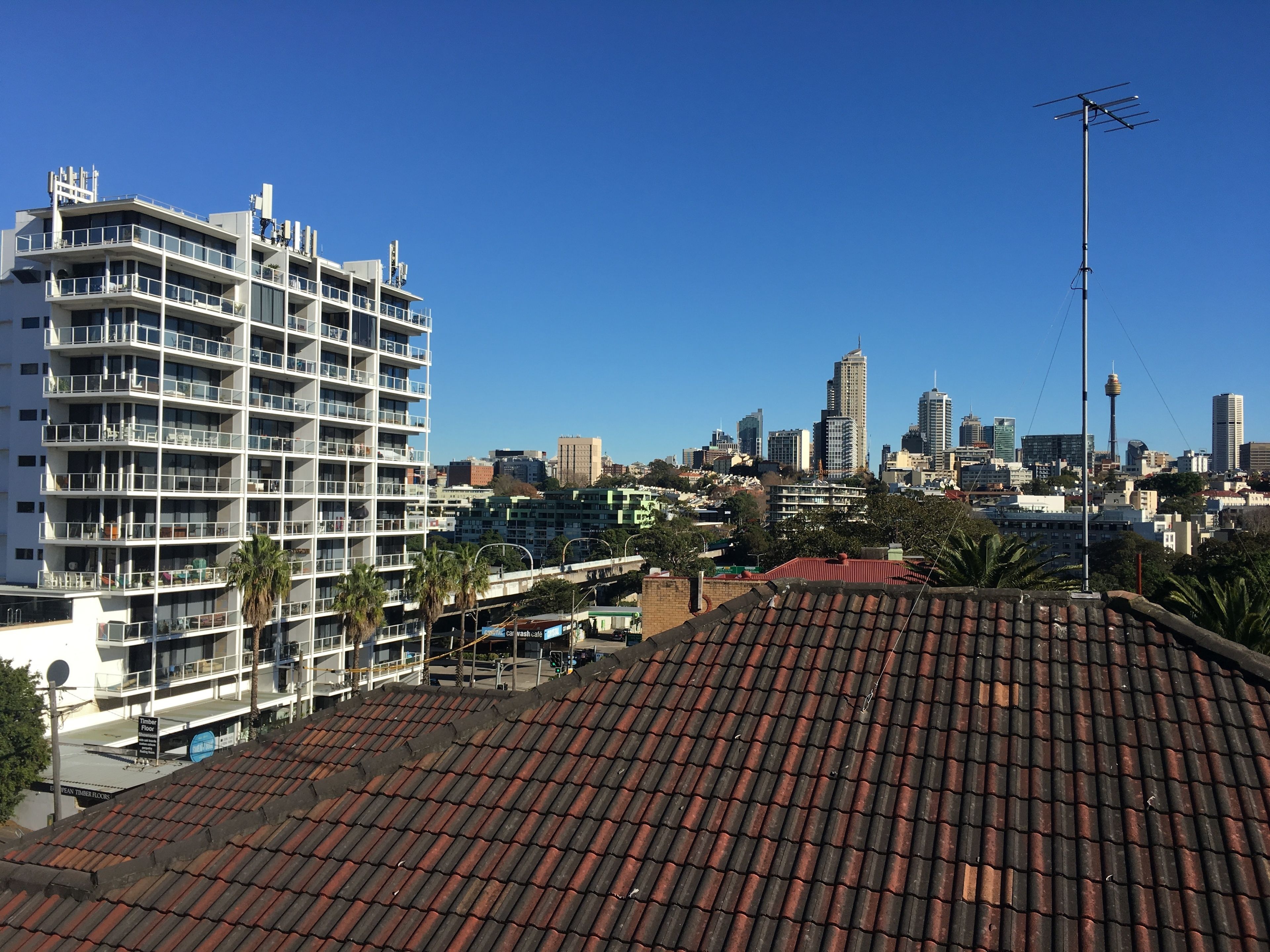 A high-rise building with multiple balconies and a city skyline in the background.