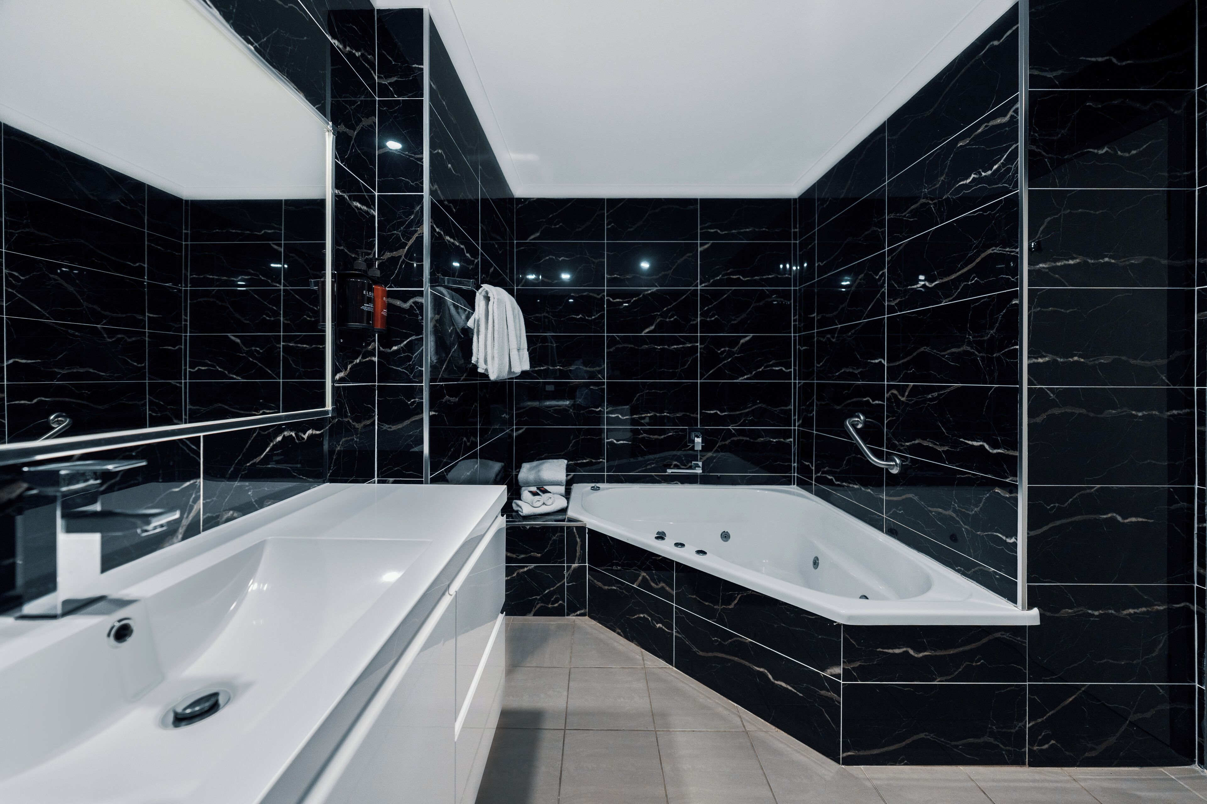 A modern bathroom with a large white bathtub, a separate sink, and a mirror.