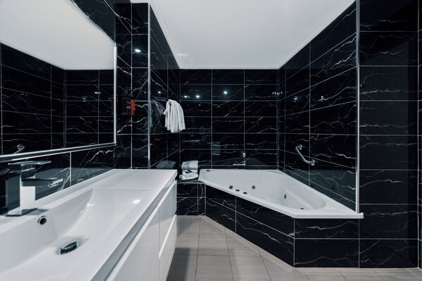 Une salle de bain moderne avec une grande baignoire blanche, un lavabo séparé et un miroir.