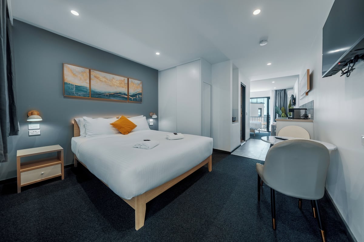 A modern hotel room with a large bed, bedside tables, a desk, and a chair.
