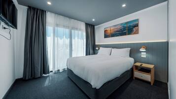 Une chambre d’hôtel moderne avec un grand lit, une table de chevet avec une lampe et un tableau au mur.