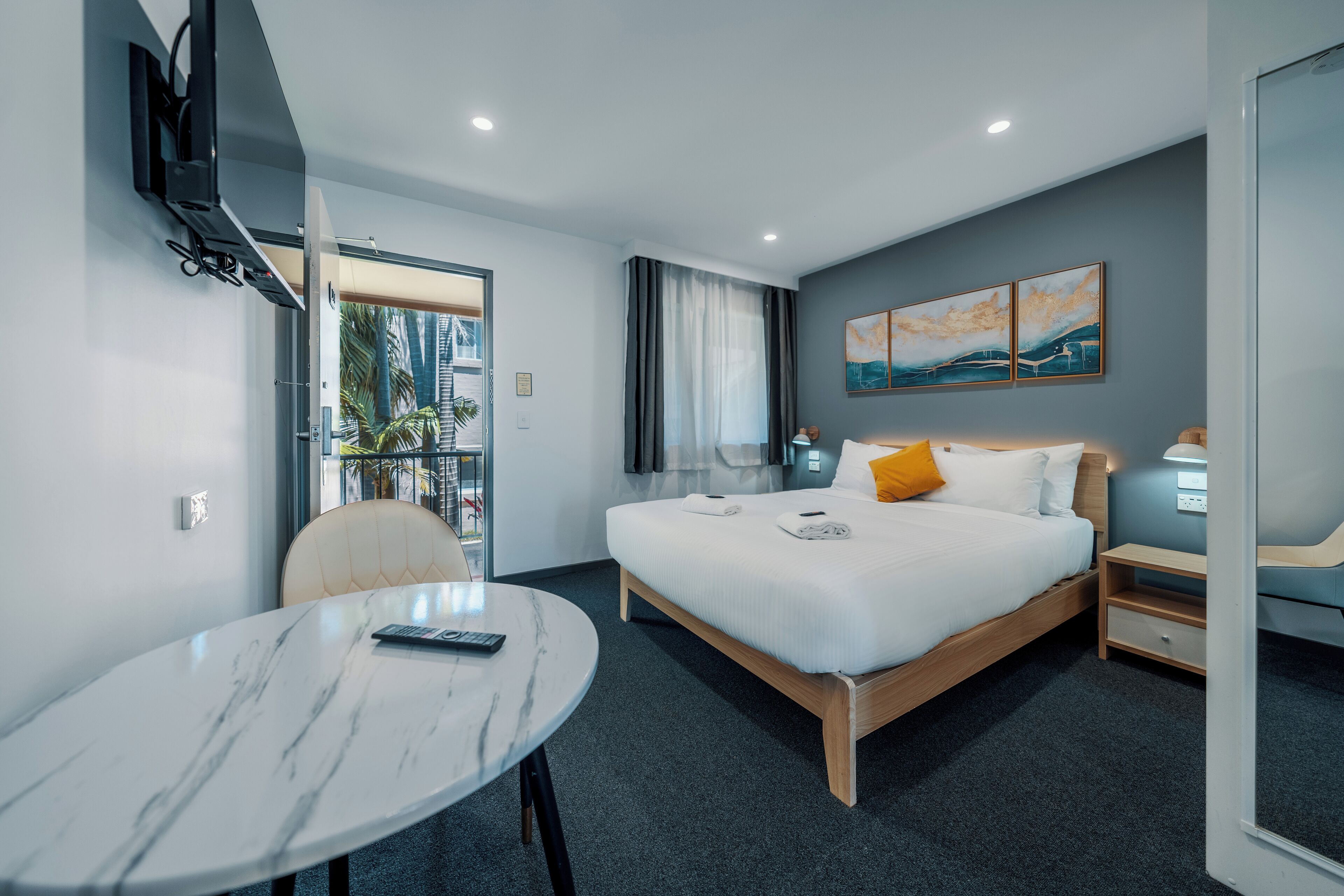 A modern hotel room with a bed, bedside table, and a round marble table.