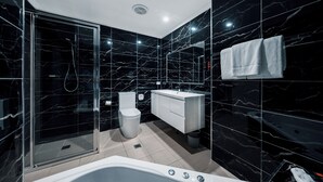 A modern bathroom with a glass-enclosed shower, a white toilet, a white vanity, and a bathtub.