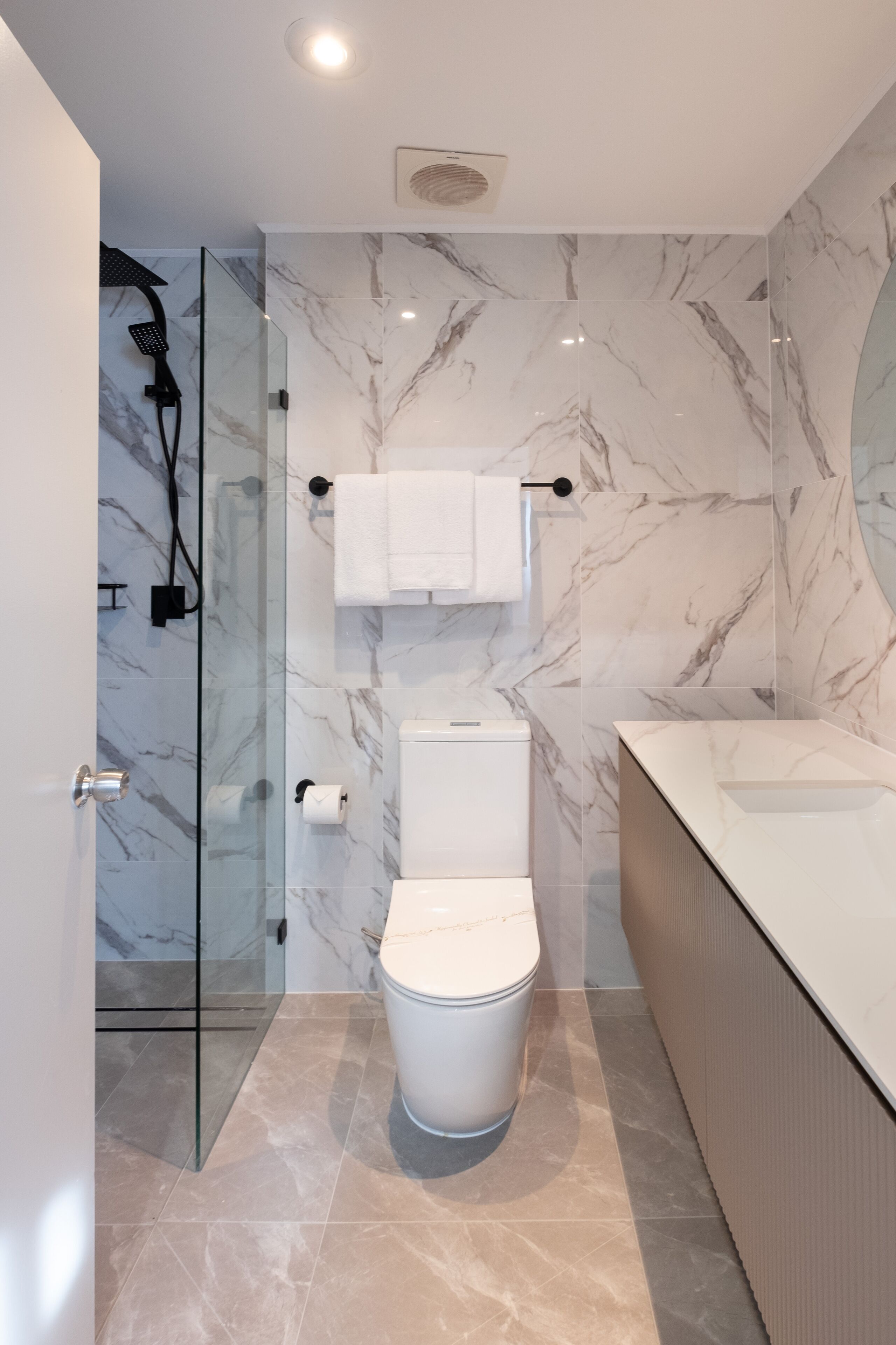 Un baño moderno con ducha de vidrio, inodoro y tocador con lavabo.