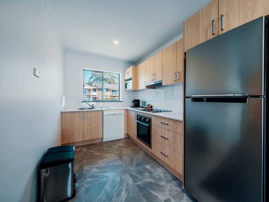 Una cocina moderna con armarios de madera, un refrigerador de acero inoxidable y un lavavajillas.