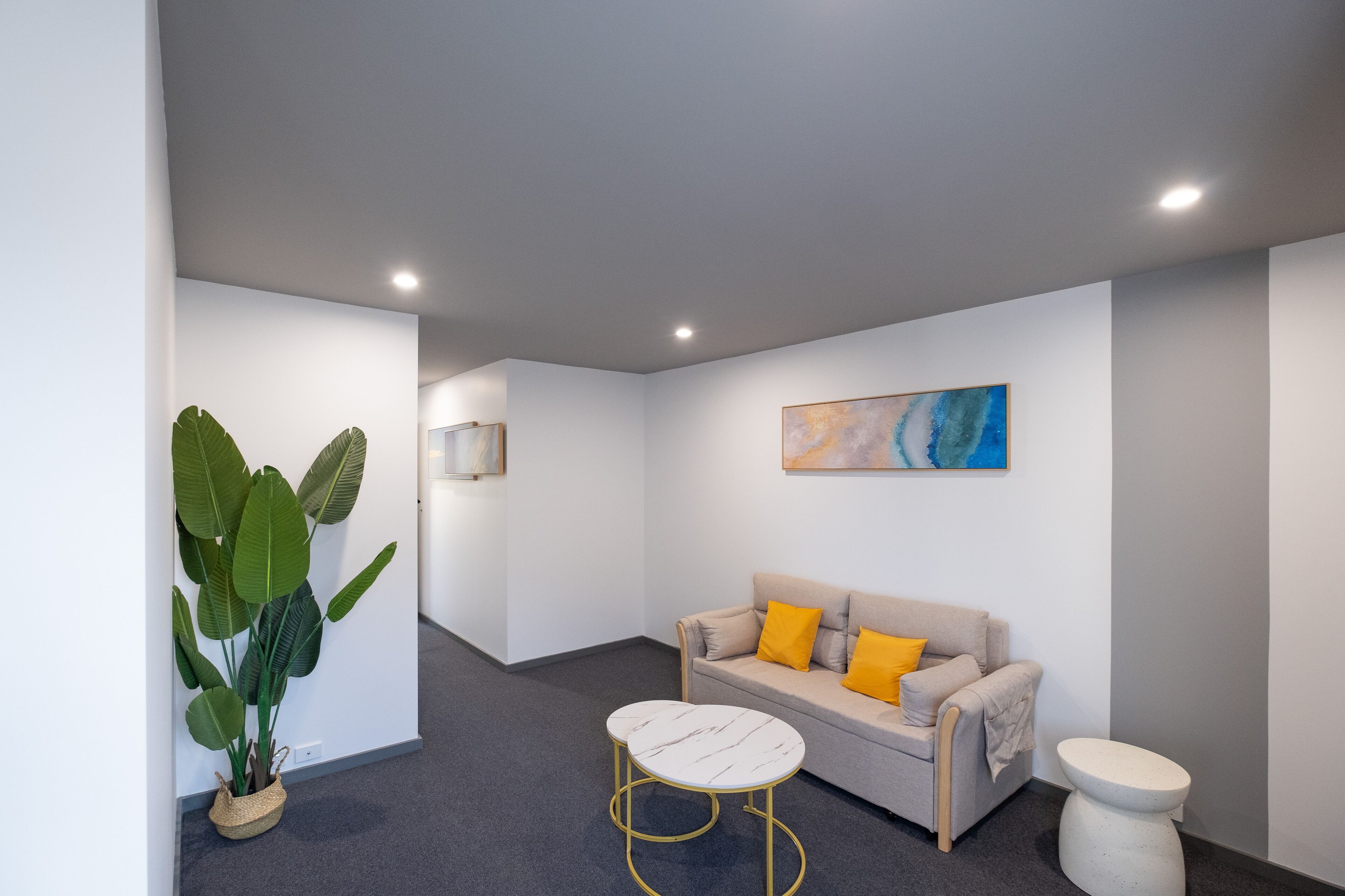 A modern, well-lit room with a sofa, a small round table, and a potted plant.