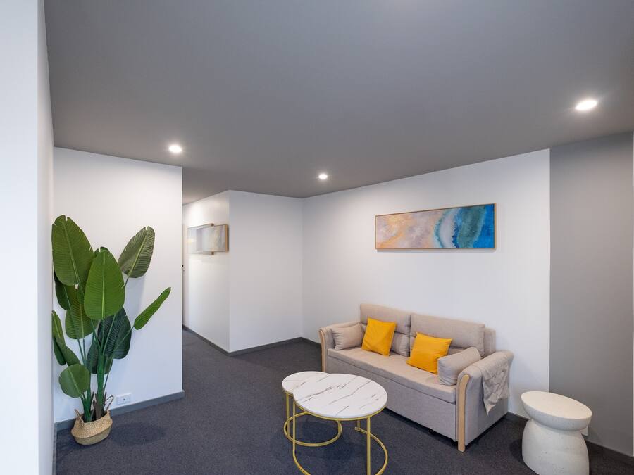 A modern, well-lit room with a sofa, a small round table, and a potted plant.