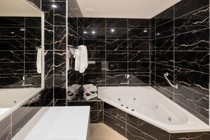 A modern bathroom with a large bathtub, a white sink, and a mirror.