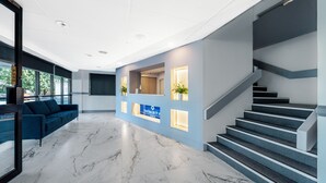A modern lobby with a marble floor, a reception desk, a staircase, and a blue sofa. - The Select Inn Penrith (Penrith)