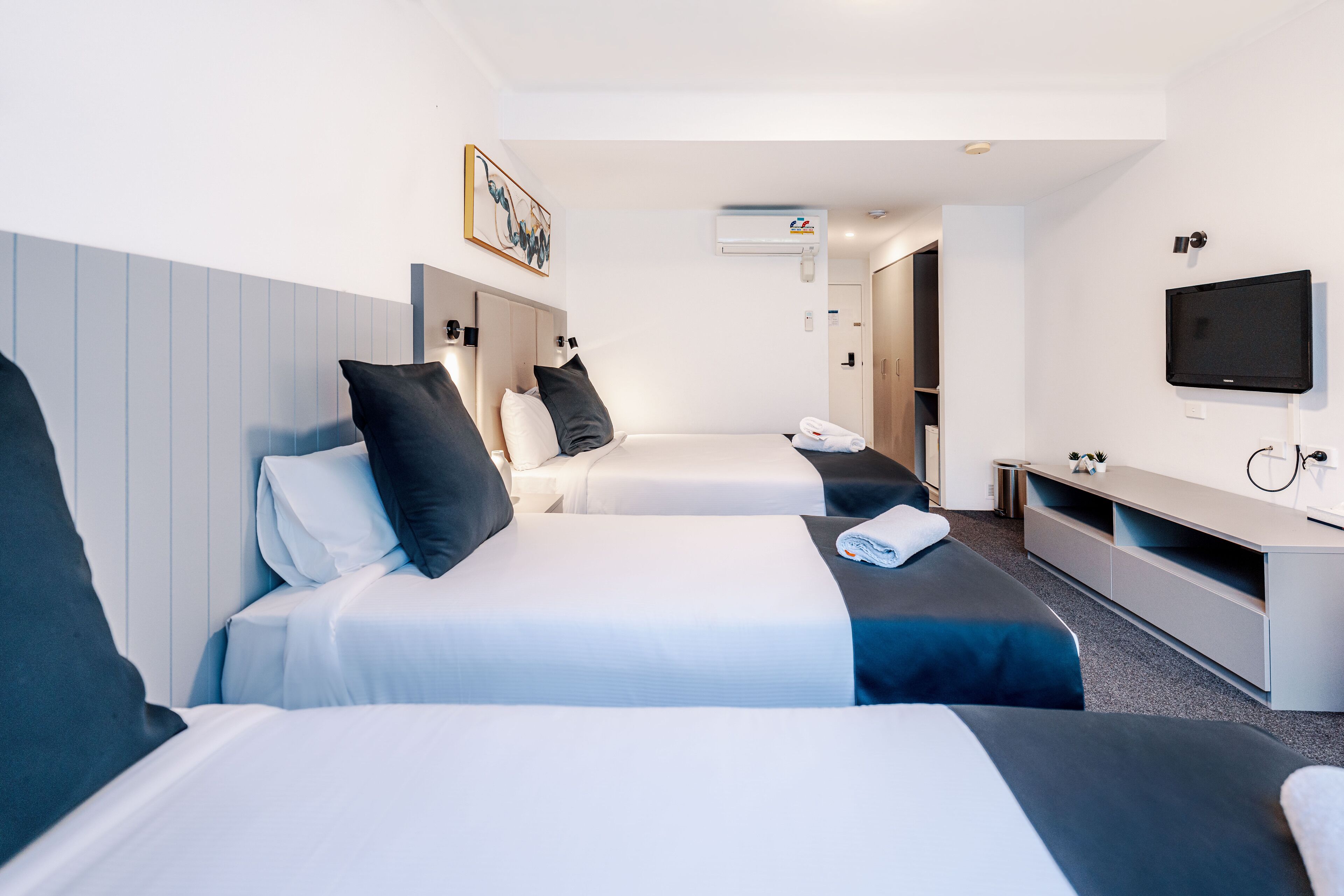 Habitació d'hotel amb dos llits, una televisió, escriptori i aire condicionat.