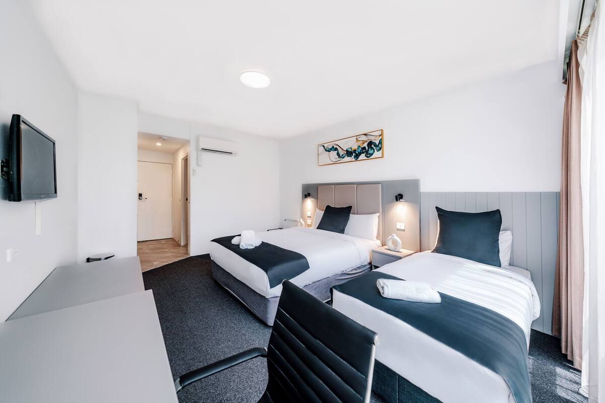 Una habitación de hotel con dos camas, un escritorio y una televisión.