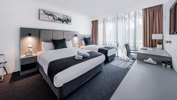 A modern hotel room with two beds, a desk, and a chair. - The Select Inn Penrith (Penrith)