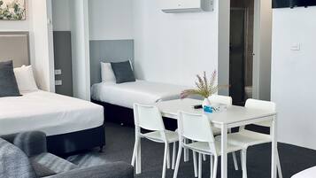 Una habitación de hotel moderna con cama, una mesita con sillas, televisor y puerta de baño.