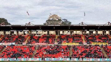 A stadium with red seating, a large logo at the top, and various advertisements.