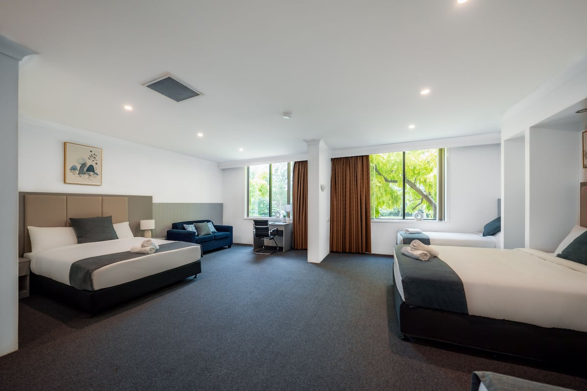 Una habitación de hotel moderna con dos camas, un escritorio y un sofá.