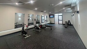 A gym with cardio machines, free weights, and a TV screen. - The Select Inn Penrith (Penrith)