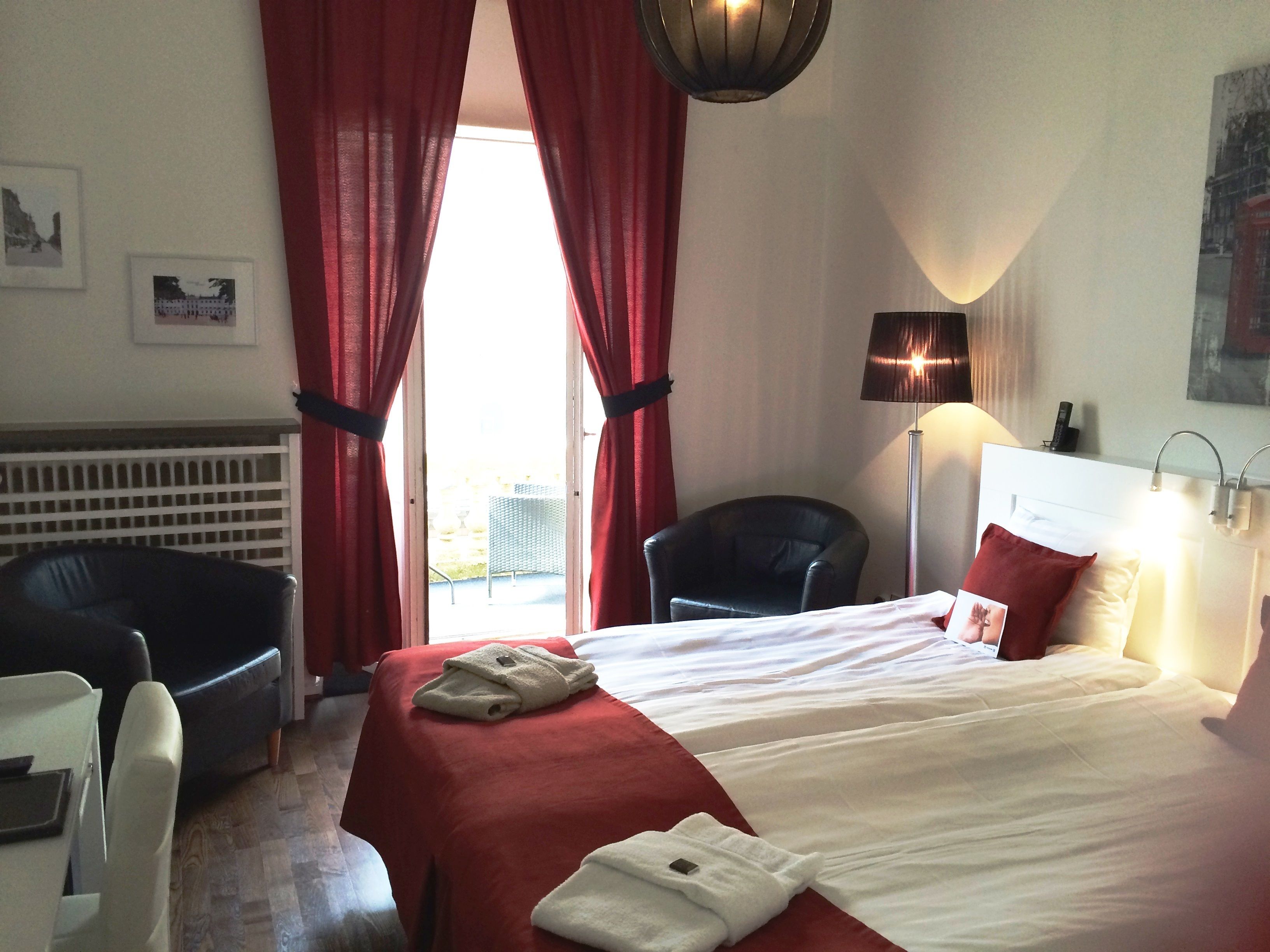 Quarto de hotel com cama, cadeira, escrivaninha e abajur.