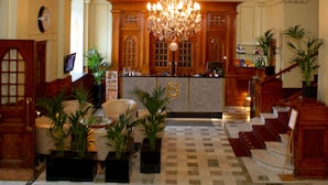 Um hall com um lustre imponente, balcão de recepção em madeira e um balcão de check-in.