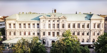 Un edificio grande y de estilo histórico con fachada simétrica, numerosas ventanas y una entrada central con arco decorativo.