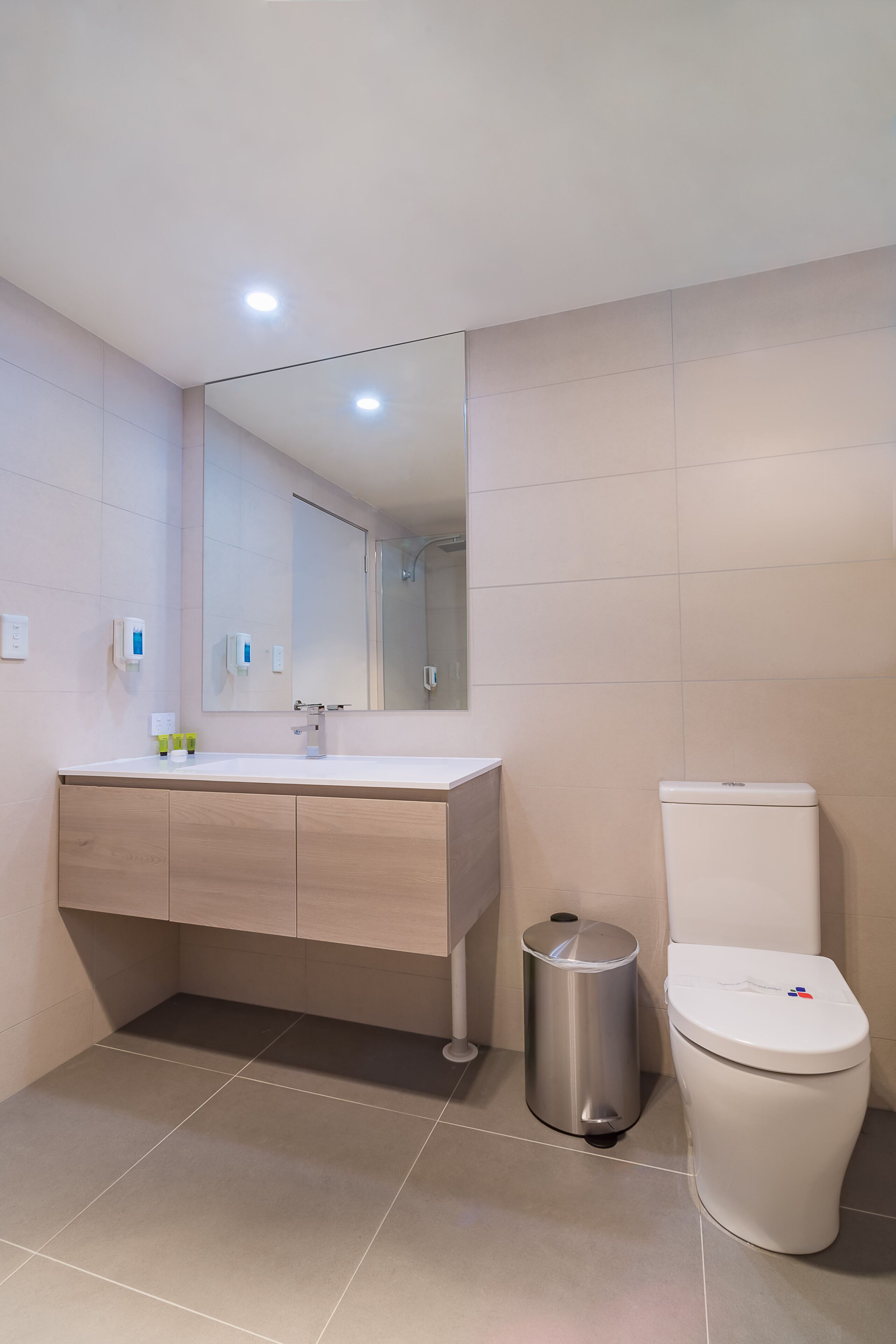 A modern bathroom with a white sink, mirror, and toilet.