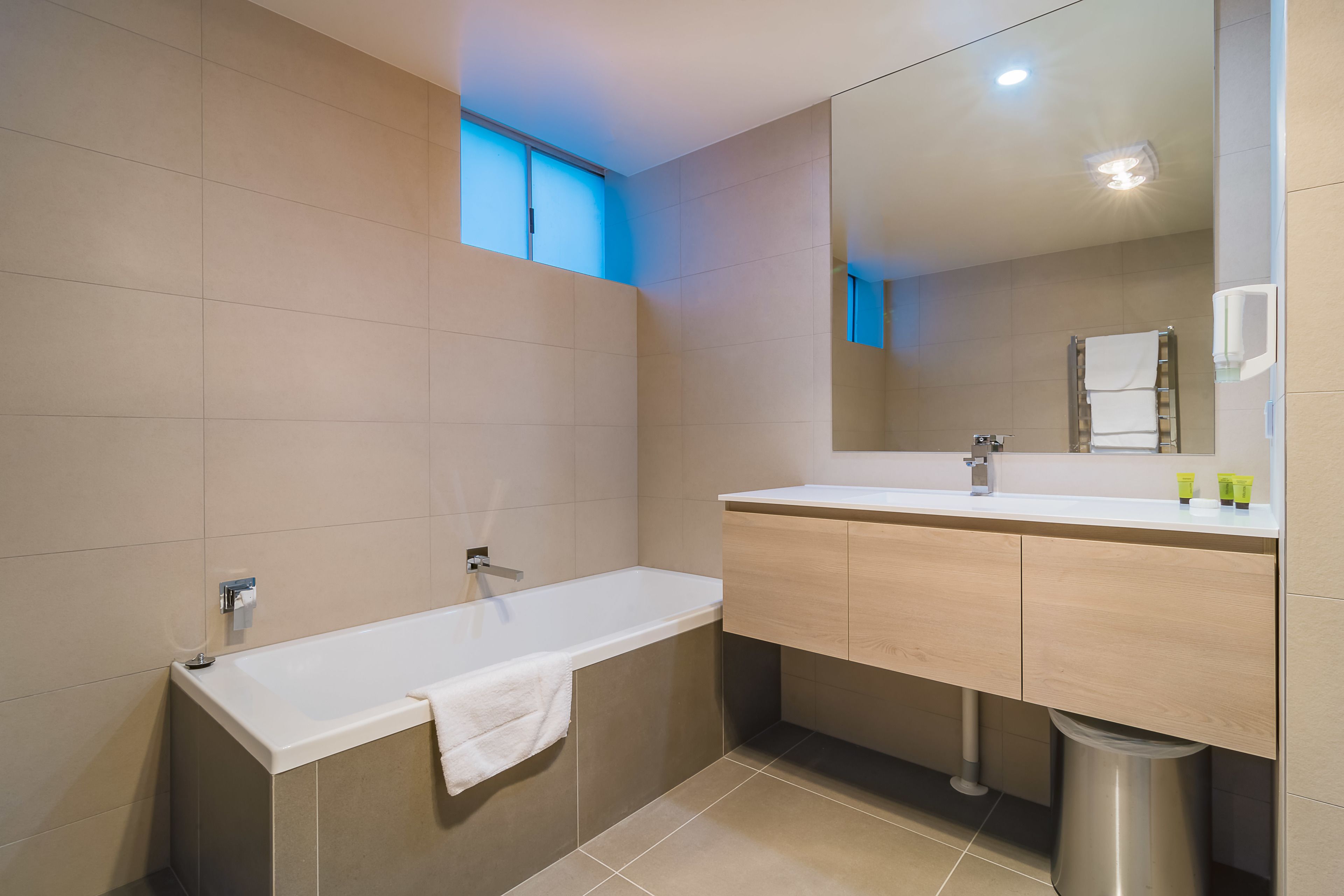 A modern bathroom with a bathtub, a sink, and a mirror.