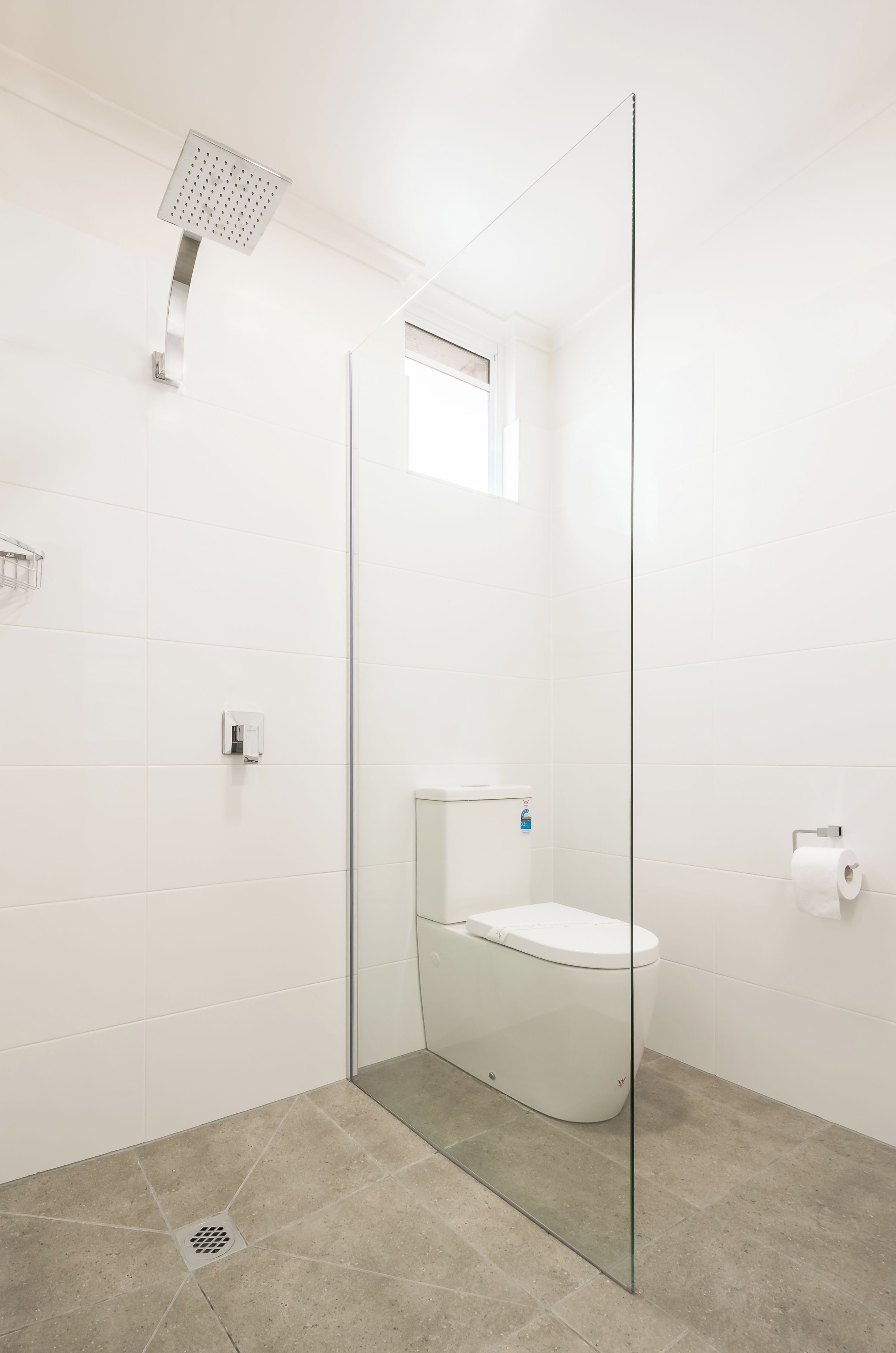 A modern bathroom with a glass-enclosed shower, a toilet, and a bidet.