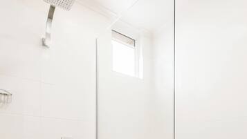 A modern bathroom with a glass-enclosed shower, a toilet, and a bidet.