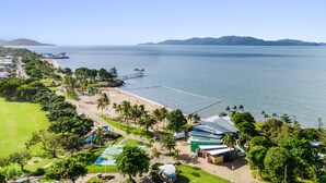 Un resort costero con playa, muelle y cancha de tenis.