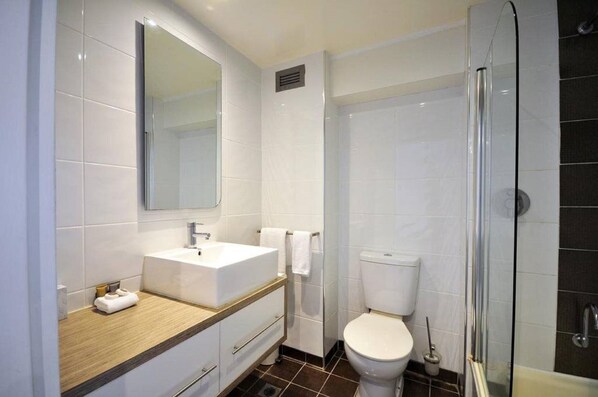 Un baño moderno con lavamanos, espejo y retrete blancos.