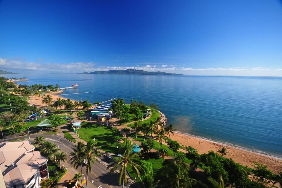 Un complejo turístico frente al mar, con playa, palmeras y un muelle.