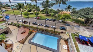 Un área de piscina con vista al océano y palmeras.