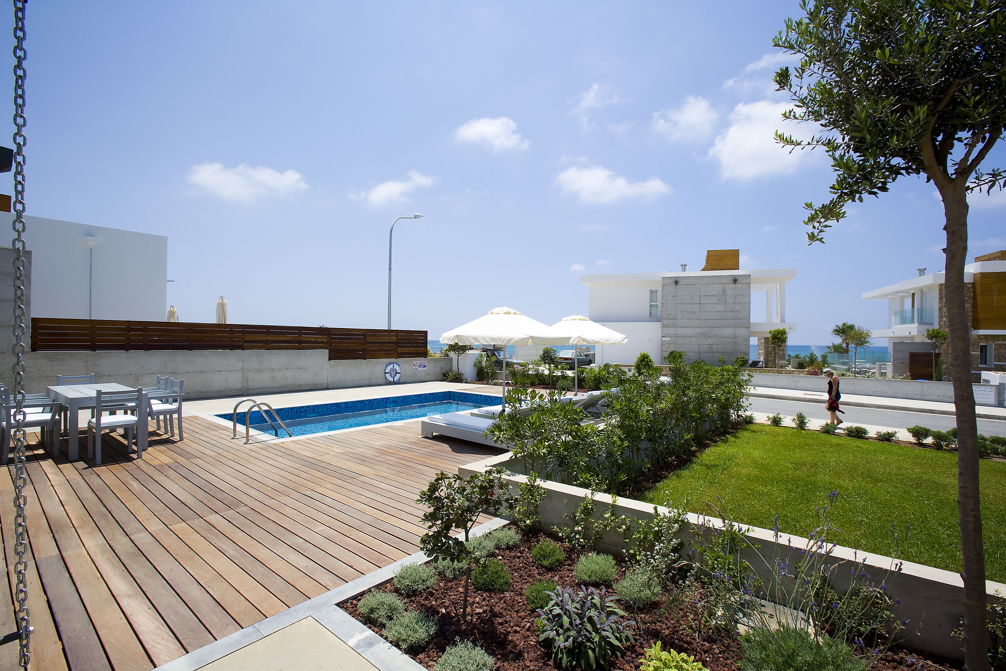 Un espace piscine extérieur moderne, doté d’une terrasse en bois, de chaises longues et d’une petite piscine.