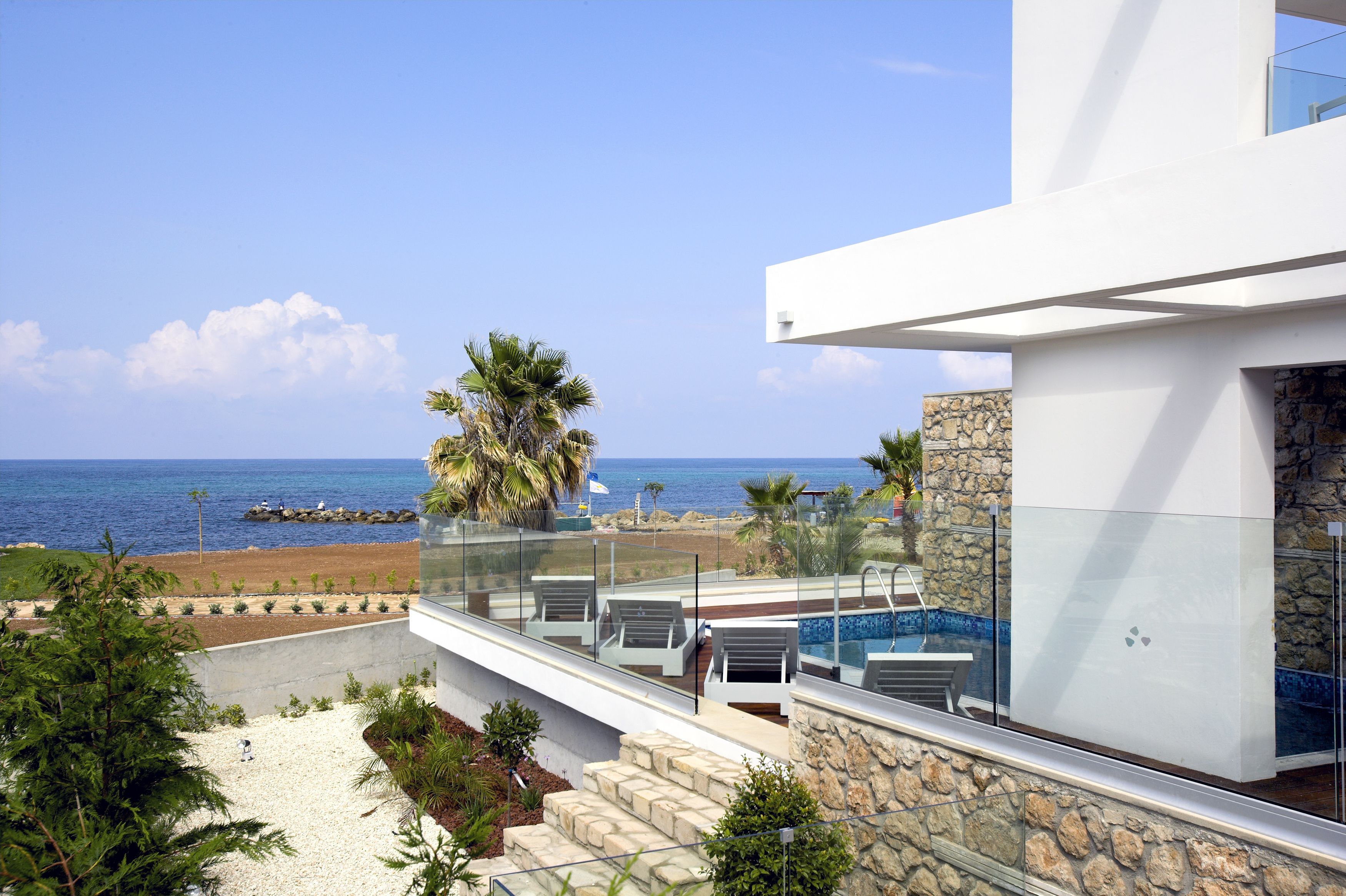 A modern building with a glass balcony overlooking a beach and the ocean.