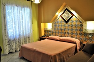 A hotel room with a bed, two bedside tables, a nightstand, and a decorative wall with patterned tiles.