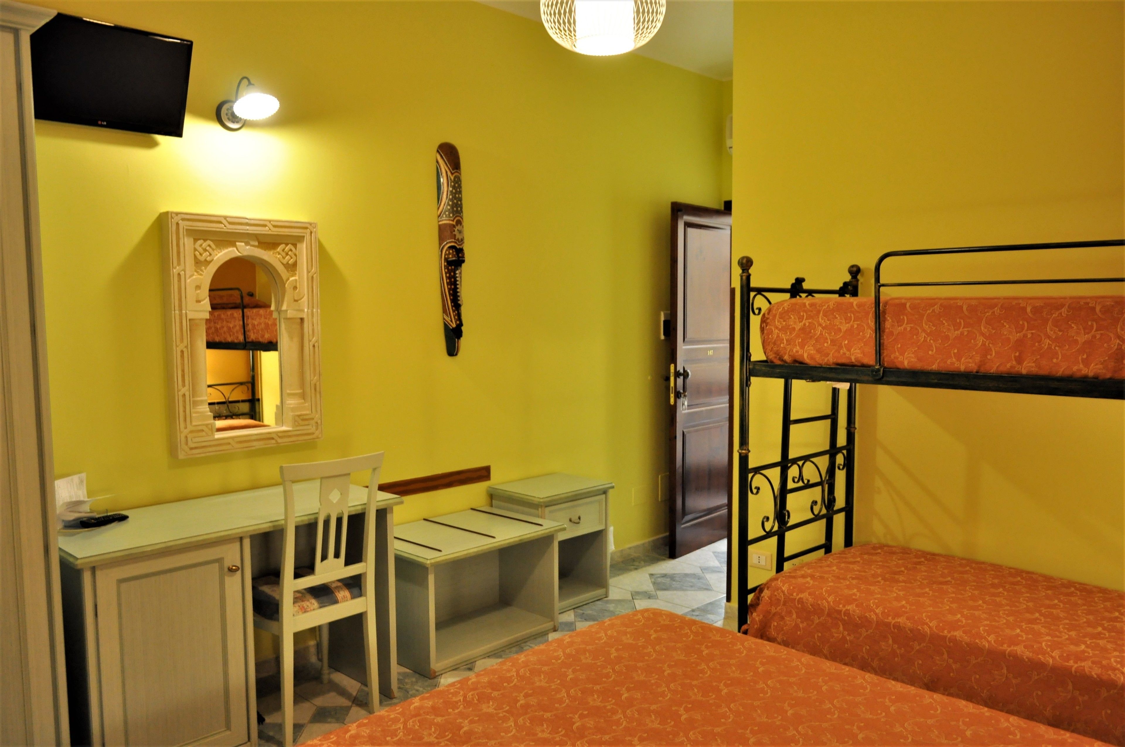 Una habitación con escritorio, silla, literas, televisor y armario.