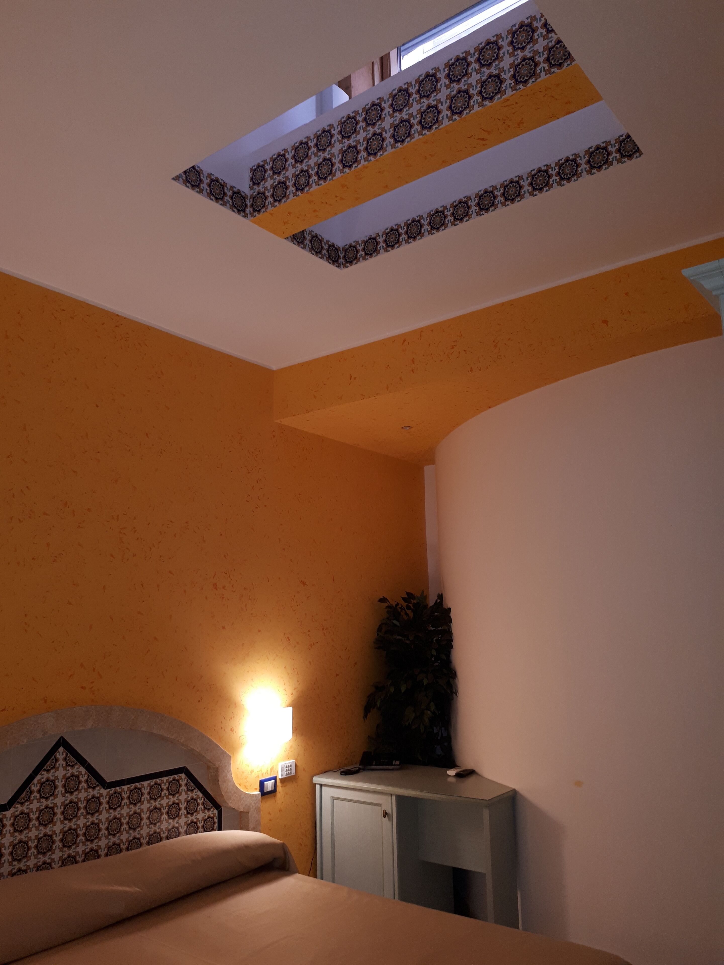 A bedroom with a bed, a bedside table, a lamp, and a ceiling light fixture.