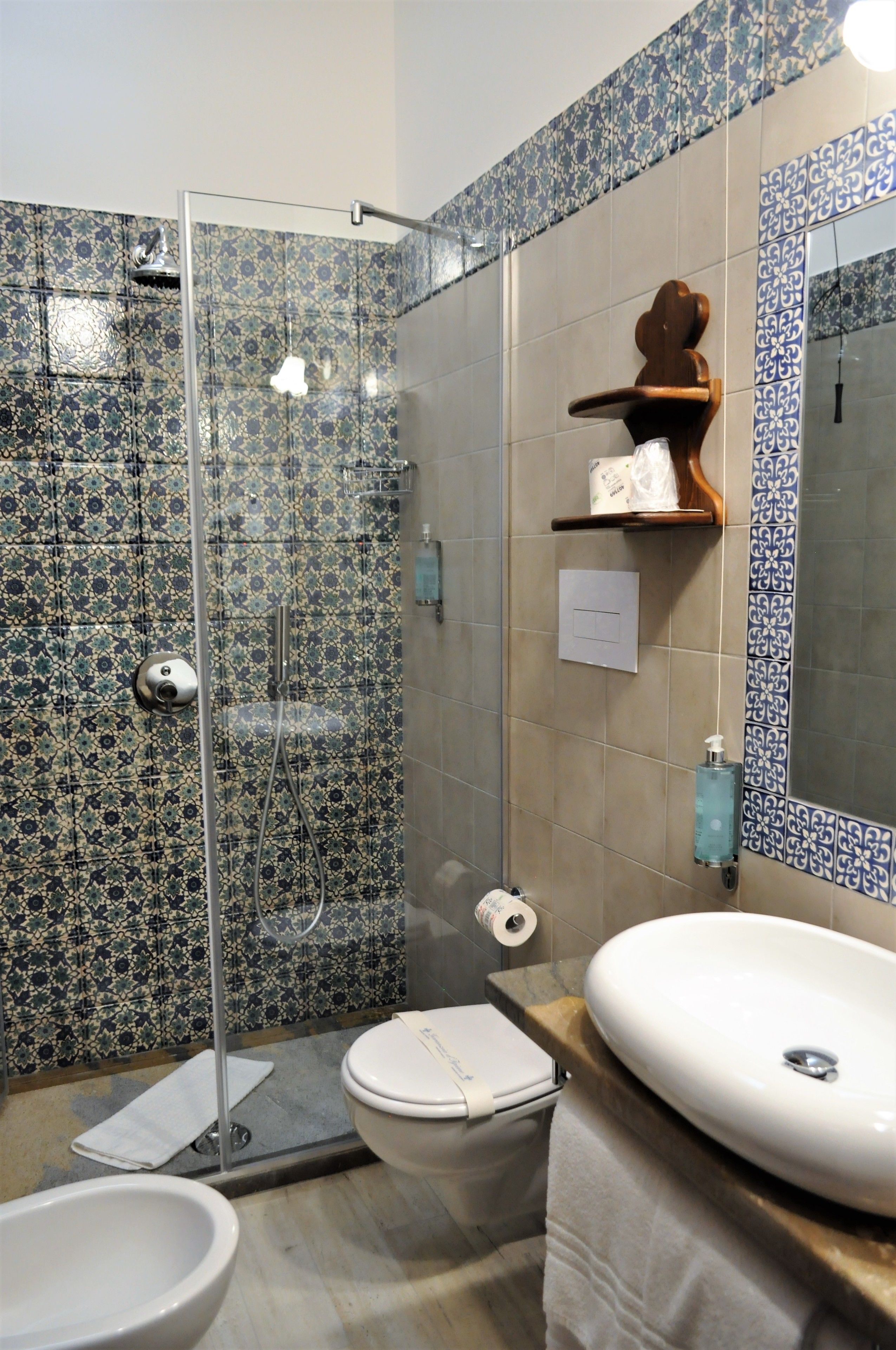 A bathroom with a shower, toilet, sink, and decorative tiles.