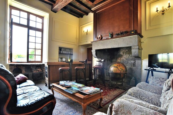 Una sala de estar acogedora con chimenea, sofás de cuero, una mesa de centro con revistas y un televisor.