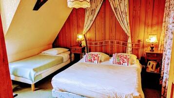 A bedroom with two beds, wooden walls, and a sloped ceiling.