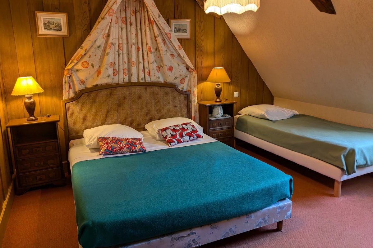 Une chambre confortable avec un lit à baldaquin, deux tables de chevet avec des lampes et une petite table de nuit.