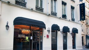 A hotel facade with large windows, a black awning, and a sign reading "HOTEL". - Hotel Petit Saint Honoré (Paris)