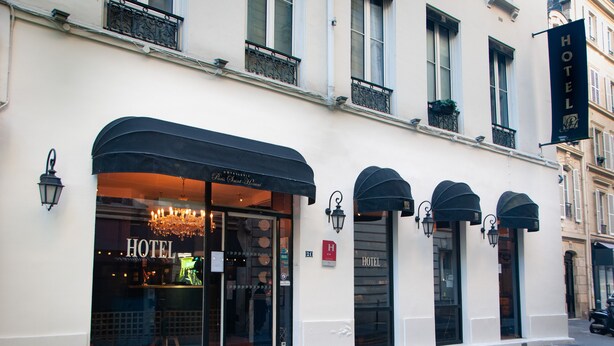 Een hotelgevel met grote ramen, een zwart luifel en een bord waarop 'HOTEL' staat.