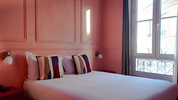 A hotel room with a large bed, two bedside tables, and a window with a balcony view. - Hotel Petit Saint Honoré (Paris)