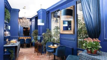 Ein Zimmer mit blauen Wänden, einem Chandelier und einem Essbereich mit Stühlen und einem Tisch.