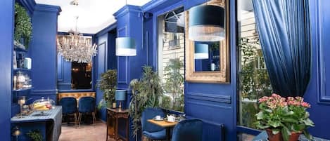 A room with blue walls, a chandelier, and a dining area with chairs and a table.
