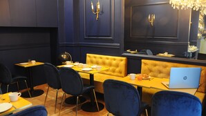 Een restaurant met donkerblauwe muren, gele zitjes en zwarte stoelen.