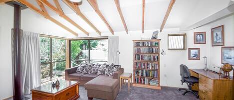 A cozy living room with a sofa, a coffee table, a bookshelf, and a desk.