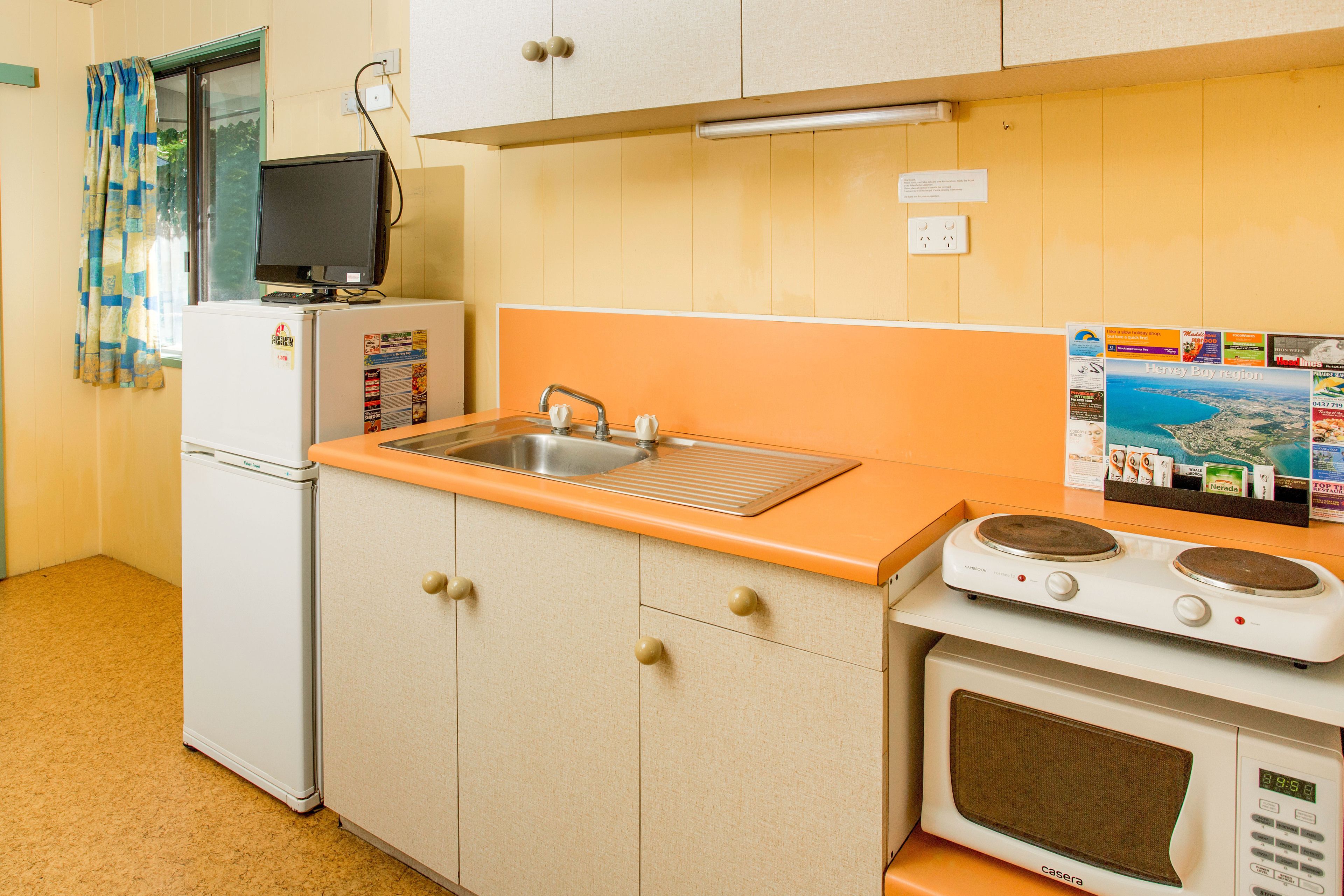 A compact kitchen with a sink, a small refrigerator, a microwave, and a stove.