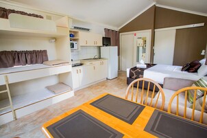 Una habitación de hotel compacta con literas, kitchenette, comedor y cama con vistas.