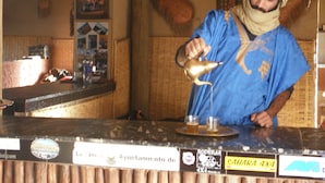 Une personne qui sert des boissons au comptoir, dans un endroit décoré avec divers panneaux et un intérieur rustique.